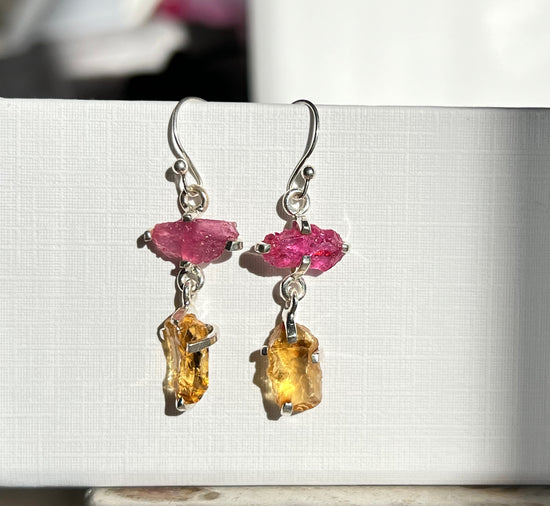 Silver earrings with pink ruby gemstones and yellow citrine drops on a white background